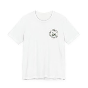 May include: White t-shirt with a circular graphic on the chest. The graphic features the text "Lazy Links Club" around a golf-themed illustration. The shirt is made of a soft material and is suitable for casual wear.