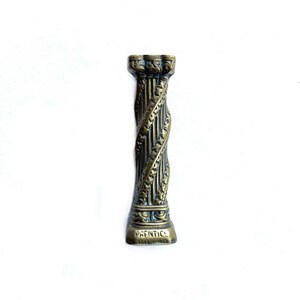 May include: A bronze-coloured decorative pillar with a twisted design and ornate detailing. The pillar has a square base with the word "PRENTICE" engraved on it. The top of the pillar has a decorative design.