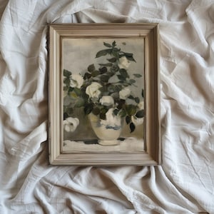 May include: A framed painting depicting white roses in a blue and white vase. The roses are arranged in a bouquet and the vase is positioned on a table. The painting has a light grey background.
