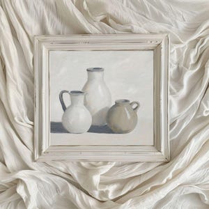 May include: A framed painting depicting three ceramic jugs. The jugs are white and beige and are arranged in a still life composition. The painting is set against a white background.