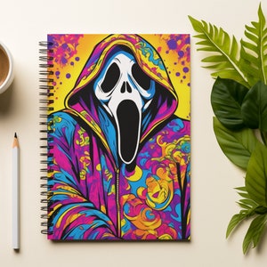 Puede incluir: Una libreta de espiral con un diseño colorido que presenta un fantasma con una sudadera con capucha. El fantasma tiene una máscara blanca con la boca muy abierta y ojos negros. El fondo es una mezcla de amarillo, rosa, azul y naranja.