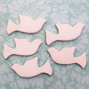 May include: Five white ceramic dove figurines, each with a simple, elegant design. The doves are arranged in a staggered pattern on a light blue background.