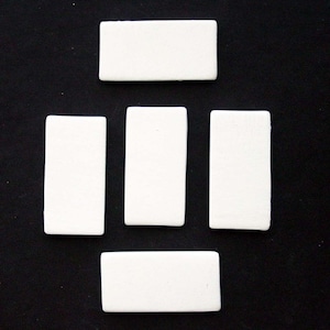 May include: Five white rectangular tiles arranged in a pattern on a black background. The tiles are all the same size and shape.