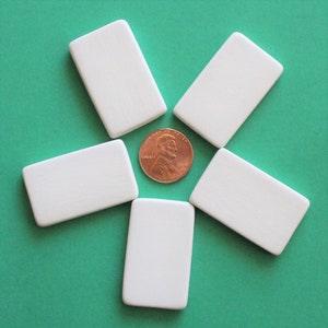 May include: Six white rectangular tiles arranged in a star shape around a copper-colored penny coin. The penny has the profile of Abraham Lincoln on one side and the Lincoln Memorial on the other.