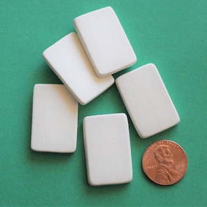 May include: Five white ceramic rectangular tiles on a green background. The tiles are approximately the size of a US penny.
