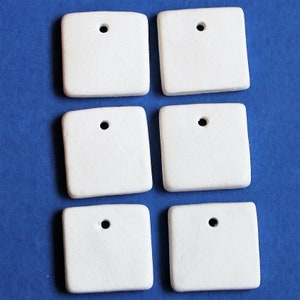 May include: Six white ceramic square tiles with a hole in the center. The tiles are blank and ready to be painted or decorated.