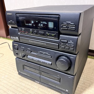 Könnte beinhalten: Schwarze Aiwa Stereoanlage mit CD-Player, Kassettendeck und FM/AM-Tuner. Das Display zeigt "16.00 FM". Sie verfügt über Tasten für Tuning, Preset und Lautstärke. Das Modell ist XG-330. Ein Vintage-Audiogerät.