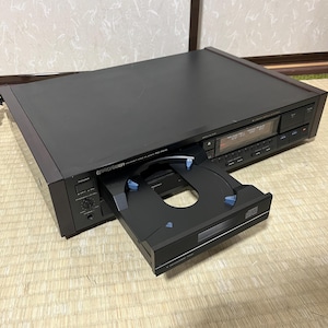 Puede incluir: Un reproductor de CD Pioneer negro con la bandeja abierta. El reproductor tiene una pantalla digital y varios botones de control. El logotipo de Pioneer es visible en la parte delantera. El reproductor de CD está sobre una superficie clara.