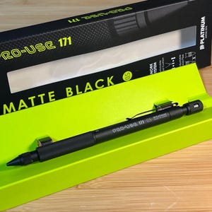 May include: Matte black PRO-USE 171 mechanical pencil with a 0.5 mm lead. The pencil is displayed in a bright green box with the text "MATTE BLACK" and "PRO-USE 171". The pencil has a textured grip and a black clip.