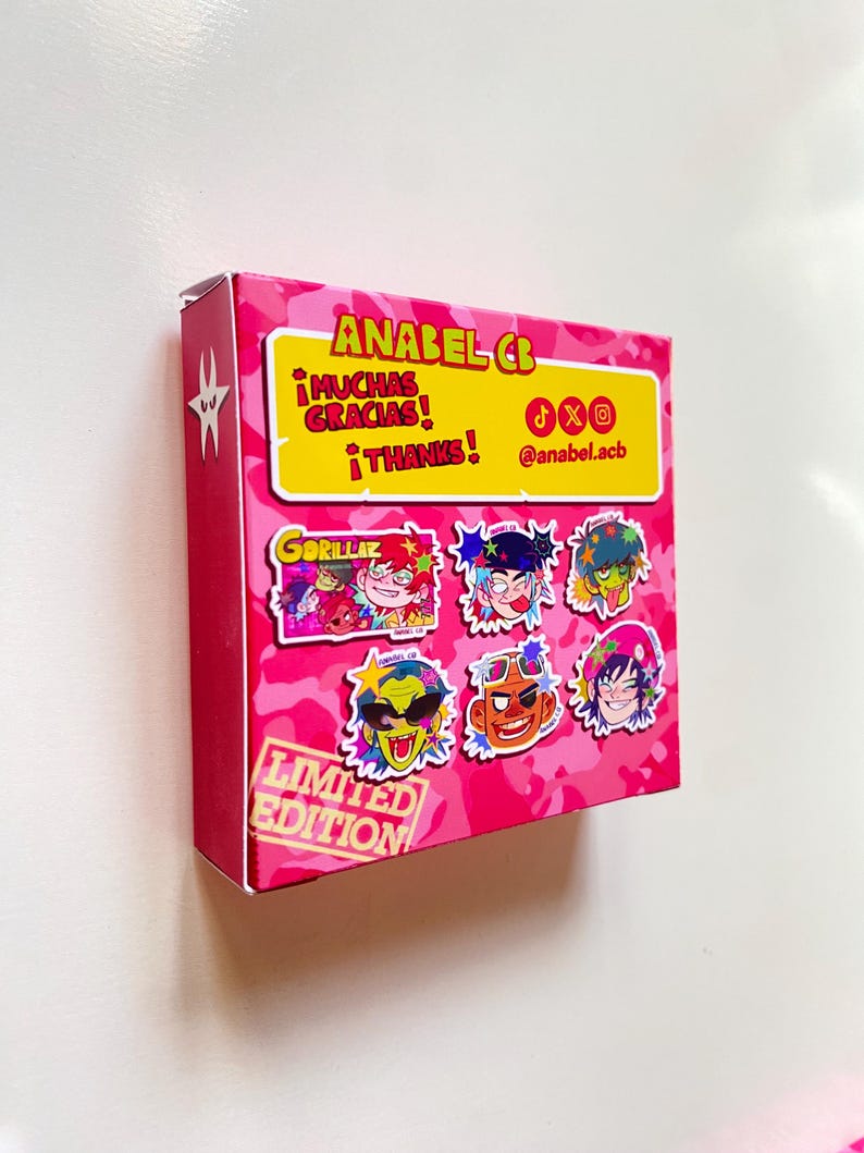 May include: A pink box with a camouflage pattern and the text "ANABEL CB" in yellow. The box features cartoon character stickers and the words "&iexcl;MUCHAS GRACIAS! &iexcl;THANKS!" in yellow. The words "LIMITED EDITION" are also visible.
