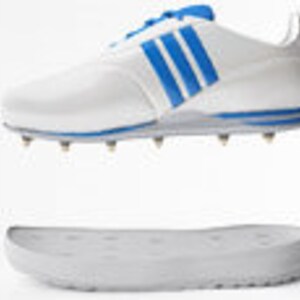 May include: White golf shoe with three blue stripes on the side, featuring a blue heel and accents. The shoe has metal spikes on the sole and a separate white sole. The shoe is designed for athletic performance.