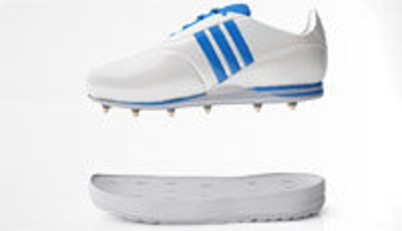 May include: White golf shoe with three blue stripes on the side, featuring a blue heel and accents. The shoe has metal spikes on the sole and a separate white sole. The shoe is designed for athletic performance.