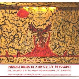 May include: A wood-burned artwork depicting a phoenix rising from flames. The artwork is framed and has a crackled finish. The text "PHOENIX RISING" is visible at the bottom of the artwork. The artwork is 21 inches wide, 20 inches tall, and 2.25 inches deep. It weighs 6 pounds. The main board is made of 1/2 inch plywood.