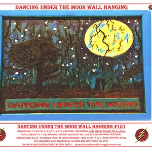 May include: Wooden wall hanging titled "Dancing Under the Moon." The artwork features a night scene with a large yellow moon, a tree, and a couple. The frame is blue, and the text "Dancing Under the Moon" is visible. Dimensions are 12.75"W x 11.5"H x 1"D.