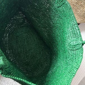 May include: A green, open-weave tote bag. The bag has a spacious interior and sturdy handles. The woven texture adds a unique, natural aesthetic. Ideal for carrying groceries or beach essentials. The bag is made from a natural material.
