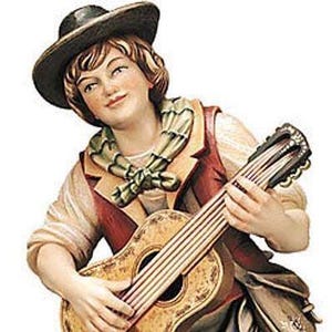 Può includere: Statuina dipinta di una persona che suona la chitarra. La figura indossa un cappello, un gilet rosso e una sciarpa. La chitarra ha una finitura marrone chiaro con una buca e corde dettagliate. La statuina è su sfondo bianco.