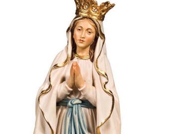 Op de afbeelding: Religieus beeldje van een vrouw met een gouden kroon en een witte jurk met gouden randen. Haar handen zijn gevouwen in gebed en een blauwe sjerp is om haar middel gebonden. Het beeld heeft een serene uitdrukking.