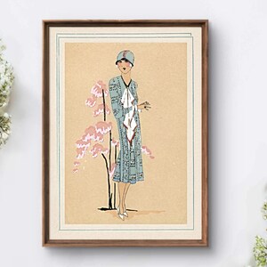 1920s Art Deco fashion illustration from Tres Parisien magazine showing a stylish woman in powder blue dress with white tie collar and matching cloche hat, standing beside pink cherry blossoms. Digital wall art from French vintage fashion publication.