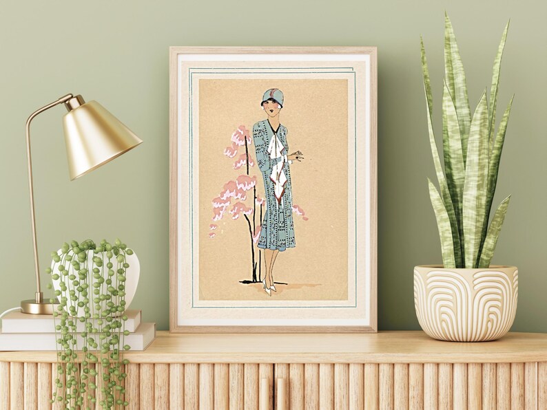 1920s Art Deco fashion illustration from Tres Parisien magazine showing a stylish woman in powder blue dress with white tie collar and matching cloche hat, standing beside pink cherry blossoms. Digital wall art from French vintage fashion publication.