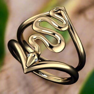 May include: A gold ring with a snake design. The snake is curled up and has two small diamonds for eyes.