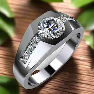 May include: A silver ring featuring a large, round, clear gemstone surrounded by smaller gemstones. The ring has a thick band and a square-shaped setting.