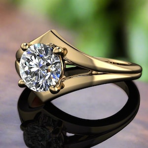 Puede incluir: Un anillo de compromiso de oro con un diamante grande, redondo y transparente. El anillo tiene un diseño único con una caña dividida y un engaste alto que resalta el brillo del diamante. El anillo está sobre un fondo borroso.