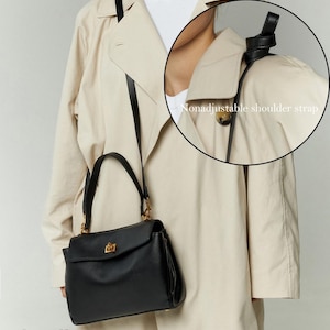 May include: A small, black handbag with a gold-colored clasp and hardware. The bag has a nonadjustable shoulder strap and a top handle. The word "Small" is printed at the bottom of the image. The bag is worn over a beige trench coat.