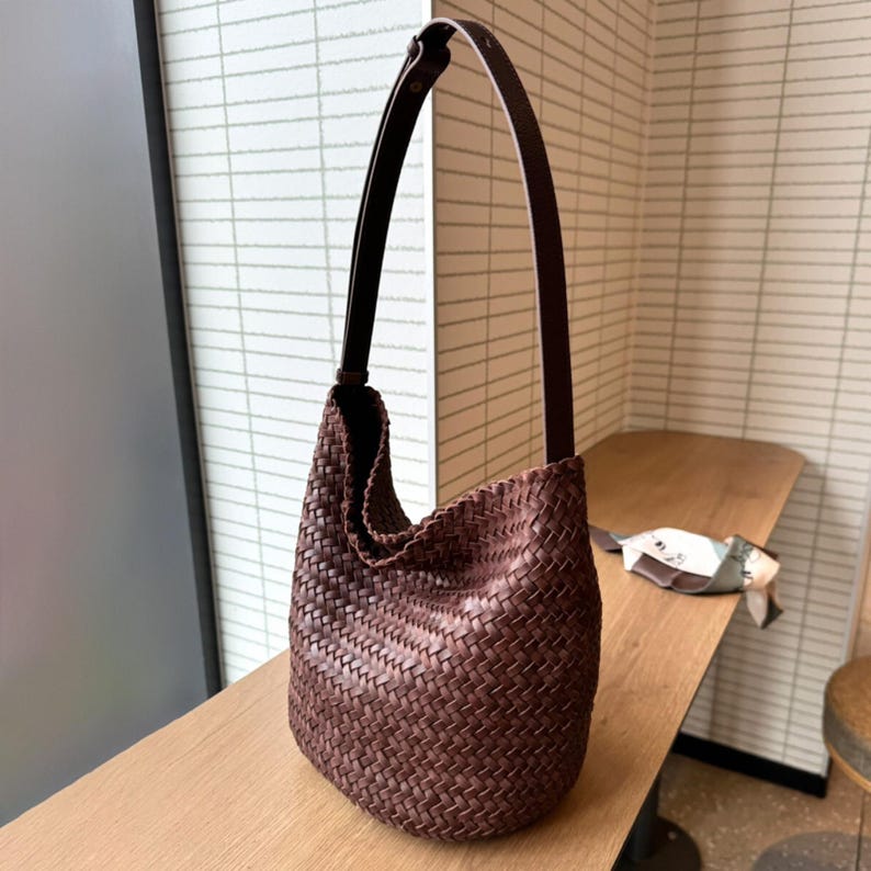 May include: A brown woven leather shoulder bag with a long strap.
