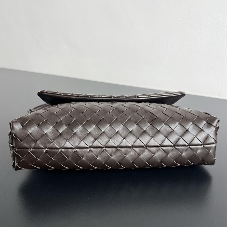 May include: A dark brown leather handbag with a woven pattern. The bag has a rectangular shape with a flap closure. The leather appears to be soft and supple, and the bag is likely a shoulder bag or crossbody bag.