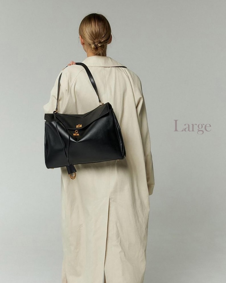 May include: A large black leather handbag with a flap closure and gold-colored hardware. The bag has a long shoulder strap and a tassel detail. The word "Large" is printed in a light purple color on the right side of the image.