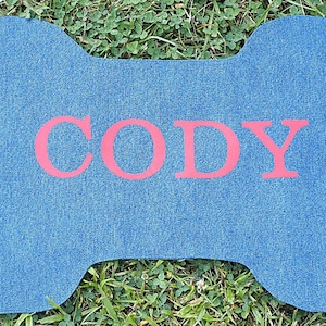 K&ouml;nnte beinhalten: Blauer Jeans-Hunde Knochen mit dem Namen "Cody" in roten Buchstaben.