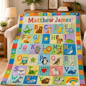 May include: A colorful alphabet quilt featuring the name Matthew James at the top. Each square displays a letter from A to Z paired with a corresponding animal or object illustration, including a bear, cat, duck, elephant, fox, giraffe, and zebra.