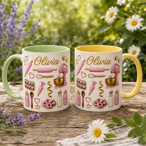 May include: Two ceramic mugs featuring the name Olivia in gold script, surrounded by pink baking illustrations including a stand mixer, rolling pin, whisk, piping bag, and donuts. One mug has a light green handle and interior, the other yellow.