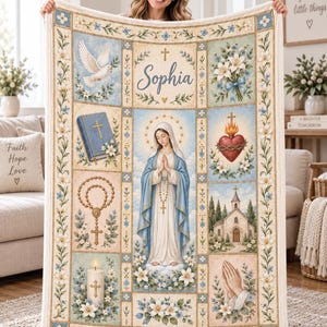 May include: A rectangular fleece blanket featuring a central illustration of the Virgin Mary surrounded by religious icons including a dove, a Bible, a rosary, a candle, a heart, a church, and praying hands, with the name Sophia printed at the top.