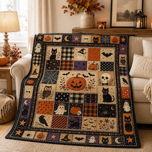 May include: A rectangular Halloween-themed quilt featuring a central pumpkin illustration surrounded by patchwork squares. The design includes black cats, ghosts, skulls, owls, bats, spiders, and pumpkins in orange, black, purple, and cream colors.