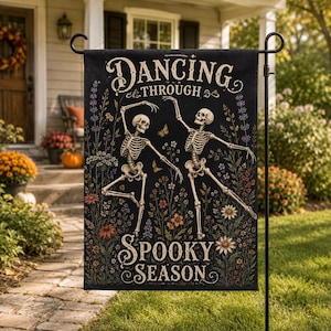 May include: A black rectangular garden flag featuring two skeletons dancing among colorful wildflowers and butterflies. The text "DANCING THROUGH SPOOKY SEASON" is printed in a decorative font at the top and bottom of the design on a metal stand.