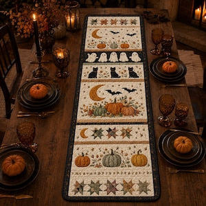 May include: A rectangular quilted table runner featuring a repeating pattern of Halloween motifs including orange and green pumpkins, white ghosts, black cats, crescent moons, bats, and multi-colored stars on a cream background with a dark border.