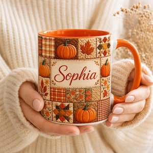May include: A ceramic mug with an orange handle and interior, featuring a patchwork quilt design of pumpkins, autumn leaves, and floral patterns in shades of orange, brown, and cream. The center displays the name Sophia in brown cursive script.