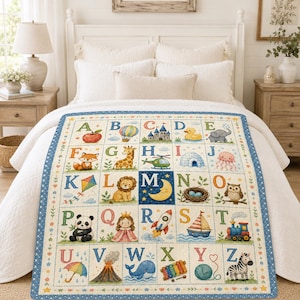 May include: A white quilt featuring a colorful alphabet grid from A to Z. Each letter is paired with a corresponding illustration, including an apple, balloon, castle, duck, elephant, fox, giraffe, helicopter, igloo, jellyfish, kite, lion, moon, nest, owl, panda, queen, rocket, sailboat, train, umbrella, volcano, whale, xylophone, yarn, and zebra.