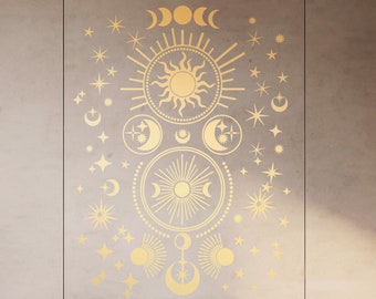 Puede incluir: Un adhesivo de pared celestial dorado con un diseño de sol, luna y estrellas. El adhesivo se aplica a una pared gris claro sobre una cabecera de madera y ropa de cama blanca.