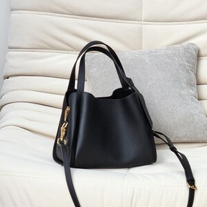 May include: A black leather tote bag with gold hardware and a long strap. The bag has a slouchy, casual look.