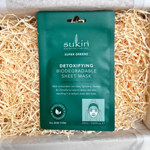 May include: A green Sukin Super Greens Detoxifying Biodegradable Sheet Mask package. The package includes the text "ALUMINIUM FREE PACKAGING" and "25ml / 0.85fl.oz. e". The mask is designed for all skin types.