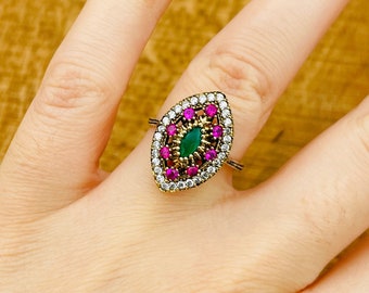 Può includere: Un anello d'argento con una pietra preziosa verde e rosa circondata da piccole pietre preziose bianche e rosa.