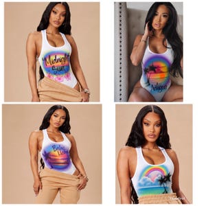 May include: A collection of four white sleeveless bodysuits featuring airbrushed graphic designs. The prints include tropical sunset scenes with palm trees, rainbows, and text reading Midnight Sun, Antigua, and Baby Llama in colorful script fonts.