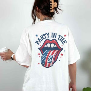 K&ouml;nnte beinhalten: Wei&szlig;es T-Shirt mit einem Grafikdruck einer rot-wei&szlig;-blauen Zunge, die aus einem Mund herausragt, mit dem Text "Party in the" drumherum.