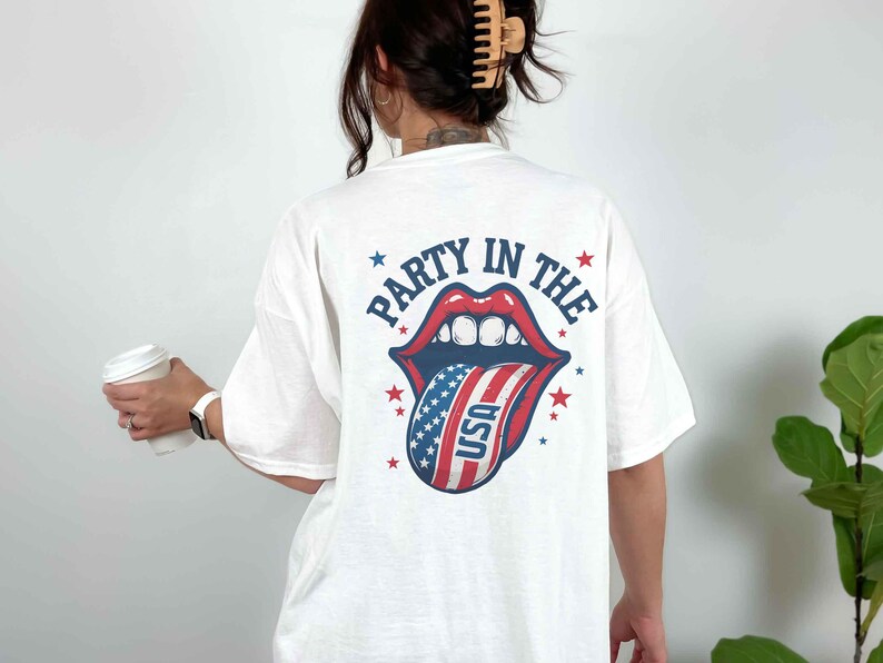 K&ouml;nnte beinhalten: Wei&szlig;es T-Shirt mit einem Grafikdruck einer rot-wei&szlig;-blauen Zunge, die aus einem Mund herausragt, mit dem Text "Party in the" drumherum.