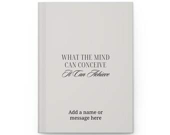May include: A light gray journal with the text "WHAT THE MIND CAN CONCEIVE It Can Achieve" in black script. The bottom of the journal has the text "Add a name or message here".