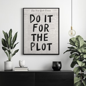 May include: A black and white print of a newspaper with the text "DO IT FOR THE PLOT" written in black marker.