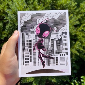 Op de afbeelding: Een roze en zwarte cartoonillustratie van een alien in een stadsomgeving. De alien staat op één been met zijn andere been omhoog. De alien heeft grote ogen en een kleine mond. De stad is op de achtergrond en bestaat uit hoge gebouwen.