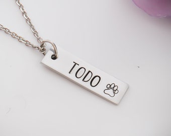 May include: Silver necklace with a rectangular pendant that says "TODO" with a paw print.